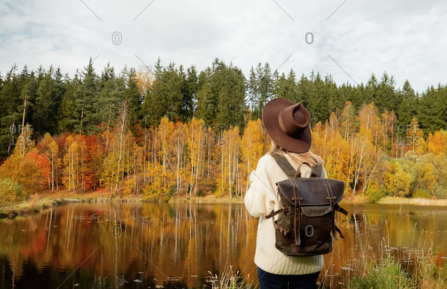 Woman with backpack stay near lake in autumn season time