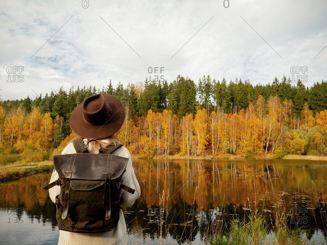 Woman with backpack stay near lake in autumn season time
