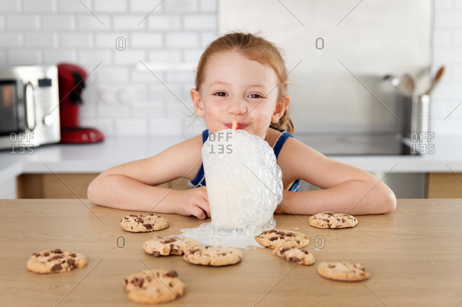 Smiling child making mess while blowing milk bubbles