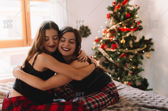 Two fun friends smiling in winter holidays near Christmas tree in cozy interior. Interior with Christmas decorations.