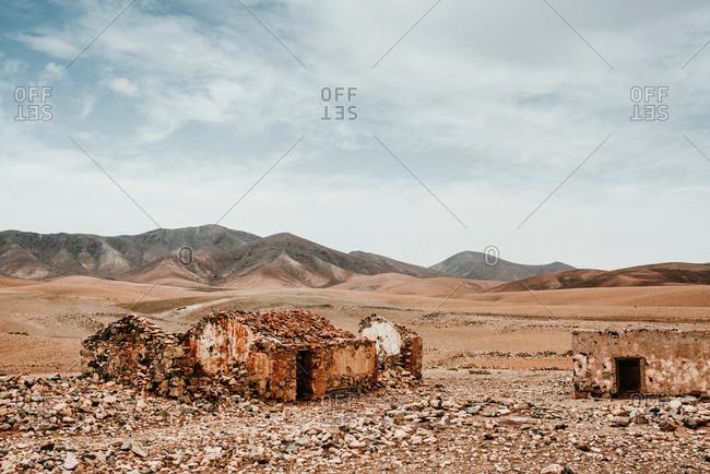 Dilapidated old buildings in mountain desert under cloudy sky