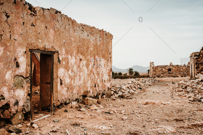 Dilapidated old buildings in mountain desert under cloudy sky
