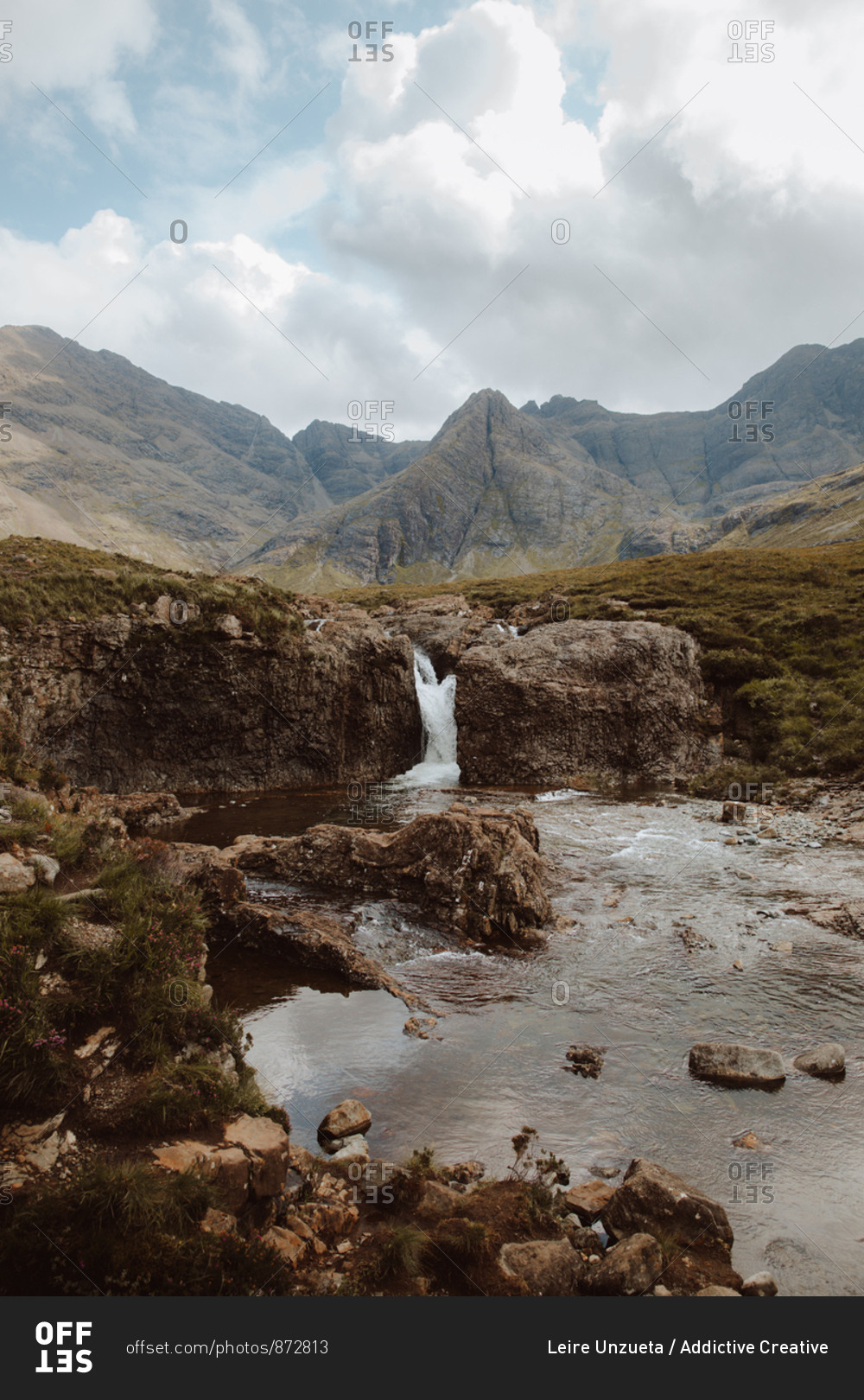 Breathtaking view of high bare mountains and water falling from rock into Fairy Pool on daytime