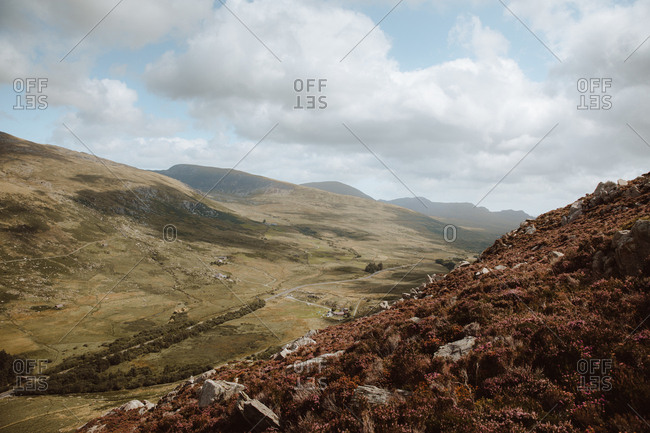 Breathtaking view of rocks and hills covered with green and brown grass and stones under overcast sky on daytime