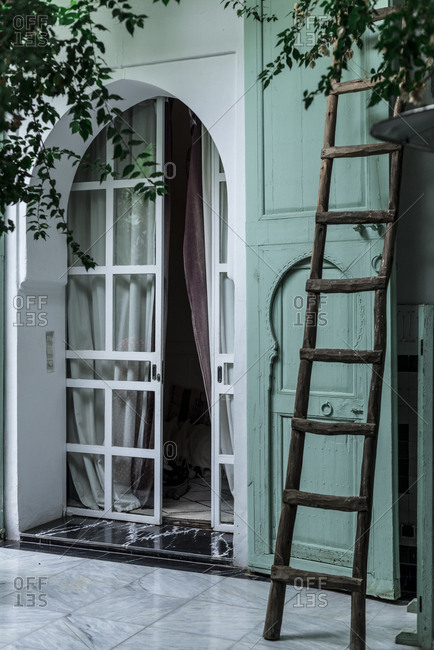 Old wooden ladder located near entrance of traditional Arabic building with green walls on street of Marrakesh, Morocco