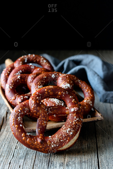 Fresh appetizing pretzels with salt arranged on scoop over old wooden surface
