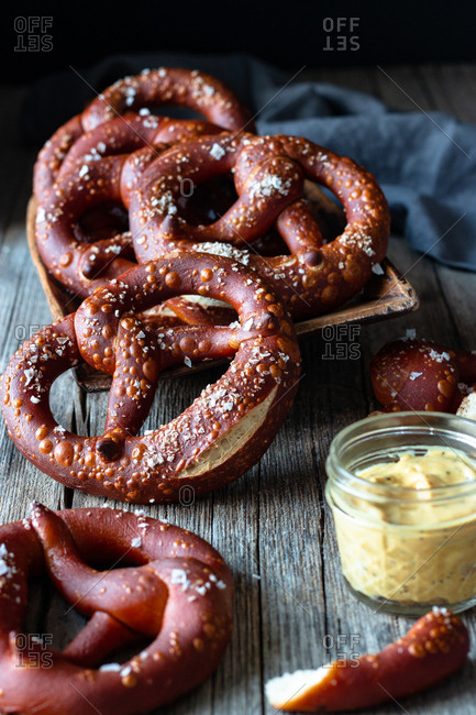 Fresh appetizing pretzels with salt arranged on scoop over old wooden surface