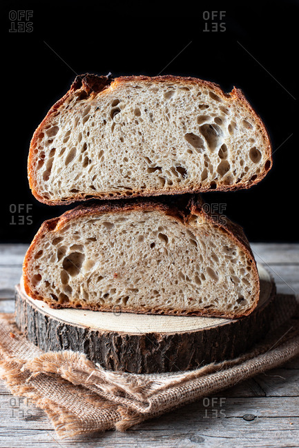 Pieces of tasty fresh bread falling on napkin on table against black background