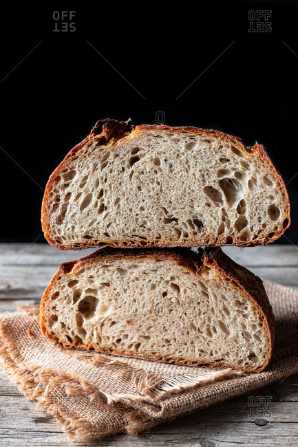Pieces of tasty fresh bread falling on napkin on table against black background