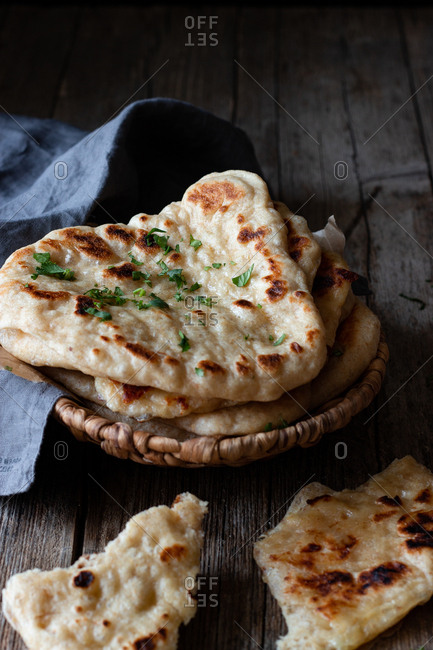 Plate with delicious naan bread and cloth napkin placed on weathered lumber table