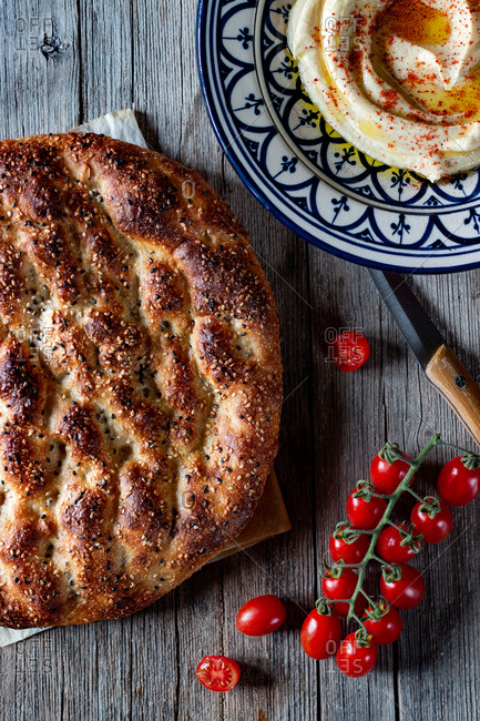 From above loaf of Ramazan pidesi placed near fresh tomatoes and spices on lumber tabletop
