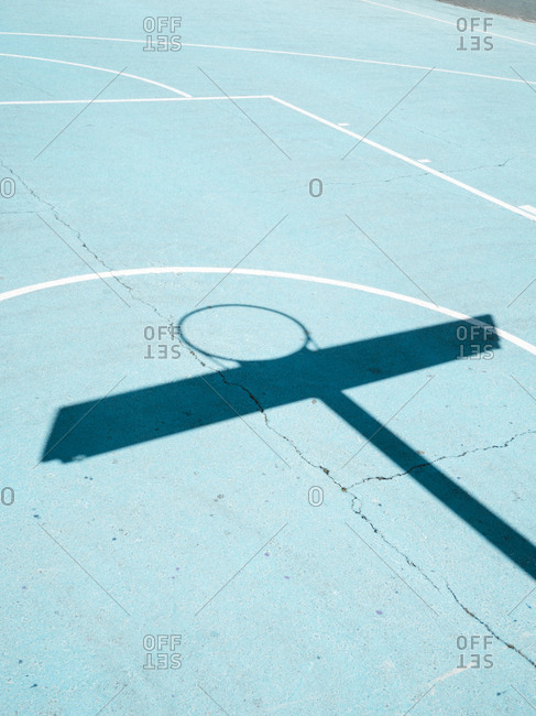 Basketball hoop shadow and white lines on blue court surface