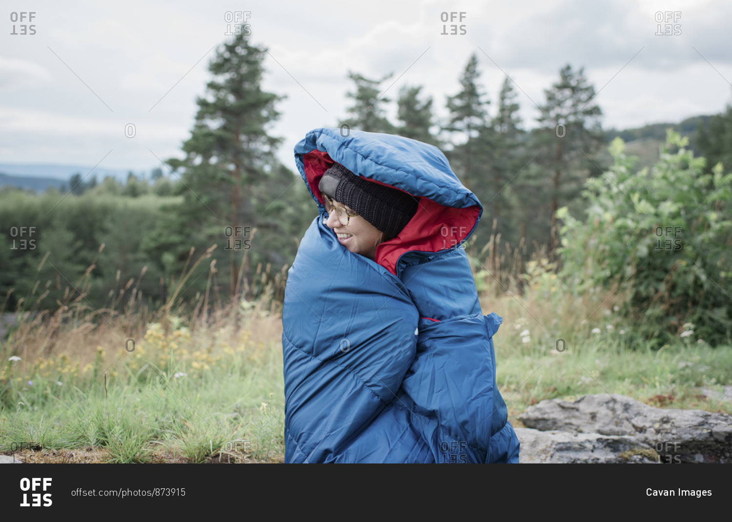 portrait of a woman wrapped in a sleeping bag whilst camping outdoors