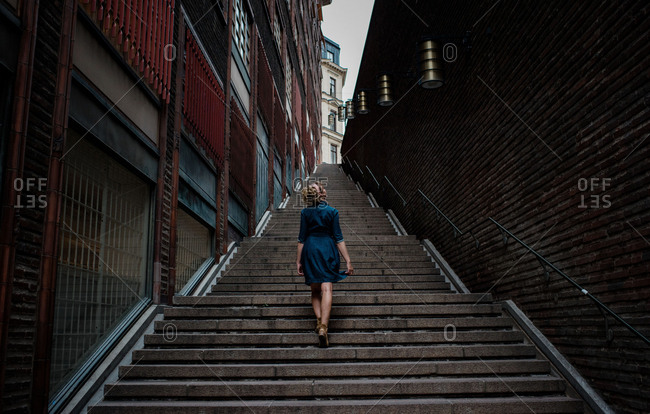 Woman in a dress walking alone up many steps in the city center