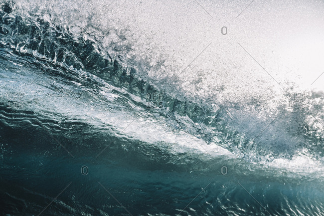 Close up of powerful backlit wave breaking against clear sky