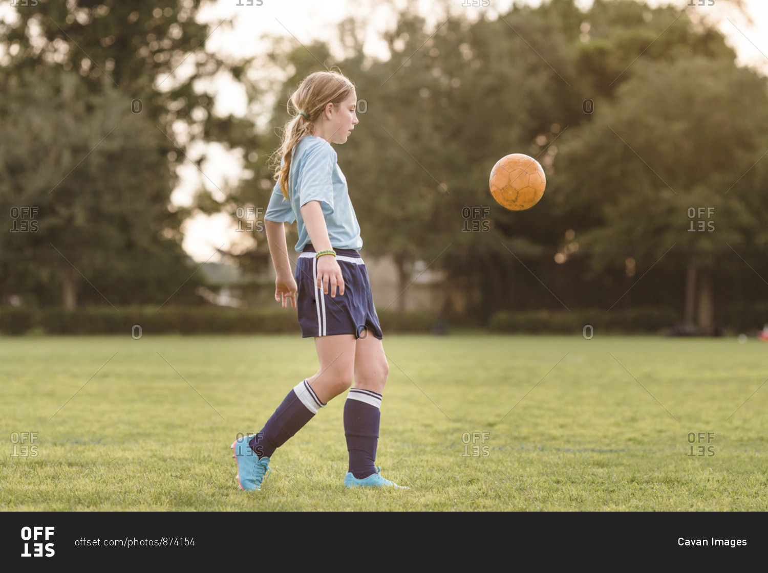 Side view of girl playing soccer at field