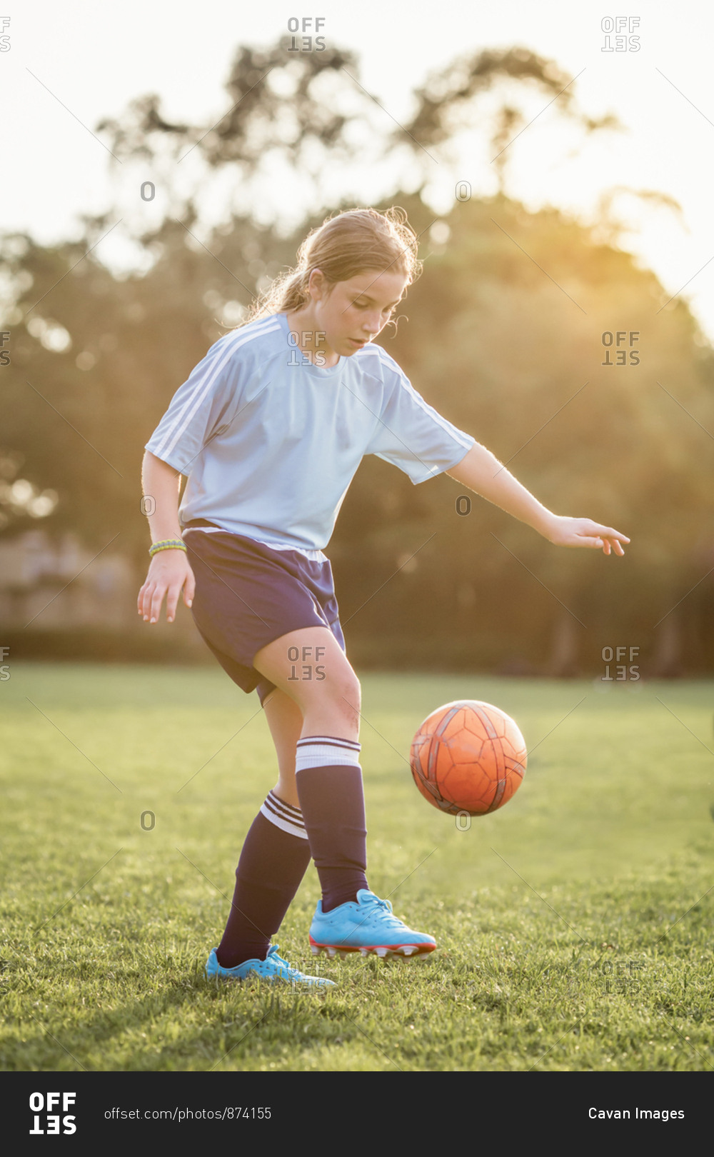 Girl kicking soccer ball while playing at field