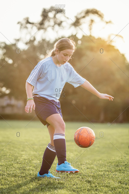 Girl kicking soccer ball while playing at field