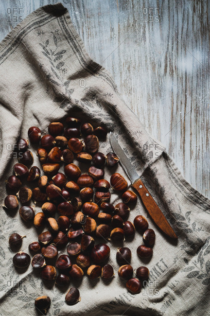 Whole sweet chestnuts on an old kitchen towel with wooden knife