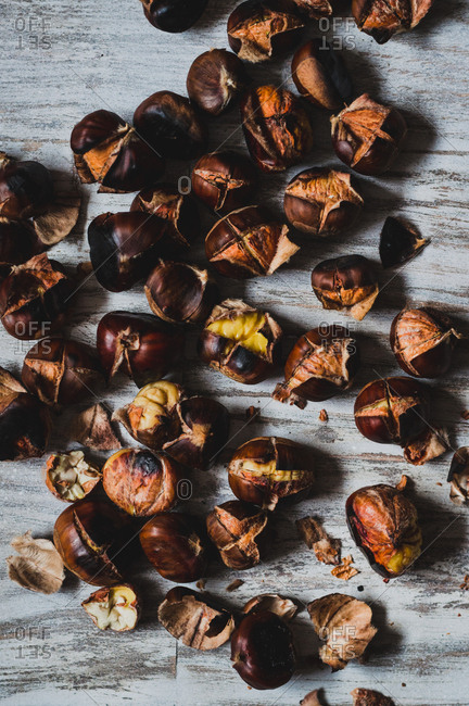 Top down view of roasted chestnuts on white wooden surface