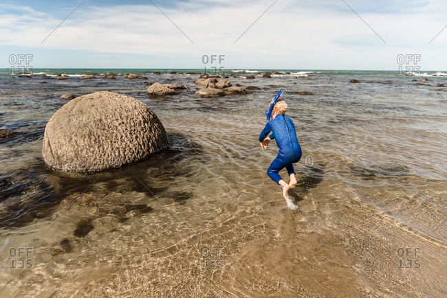 Young boy diving into water with snorkel on the coast of New Zealand