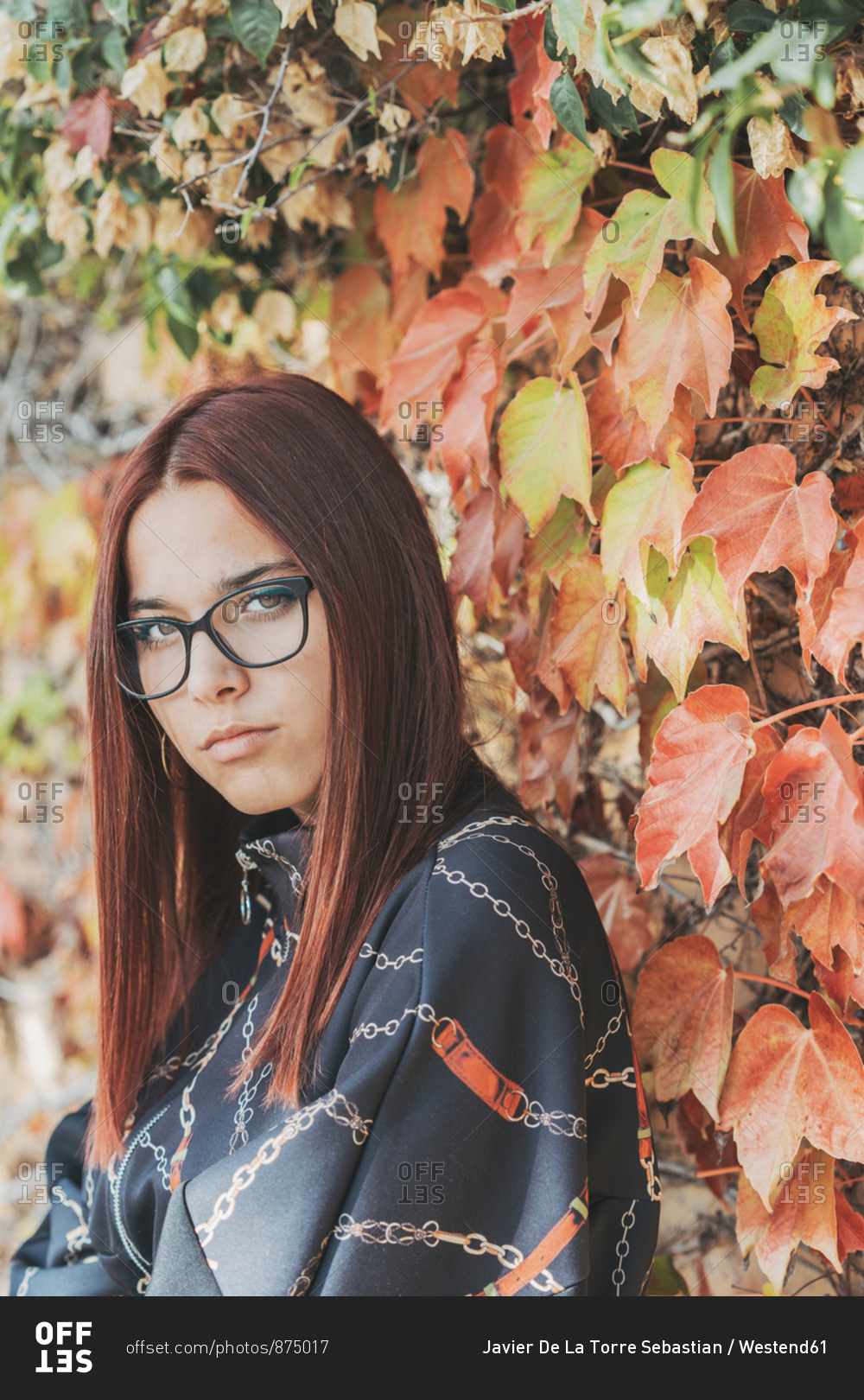 Portrait of teenage girl with dyed red hair in front of greening in autumn