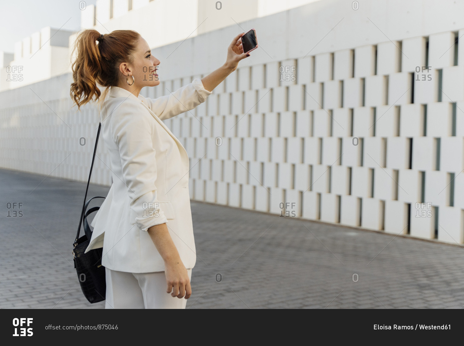 Businesswoman in white pant suit- taking smartphone selfie