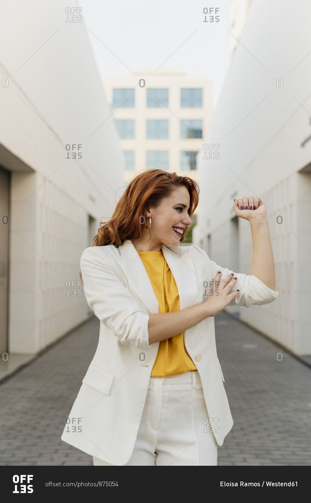 Energetic businesswoman in white pant suit- flexing her muscles