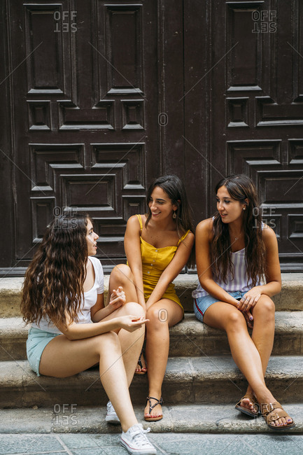 Three female friends sitting on a stoop talking