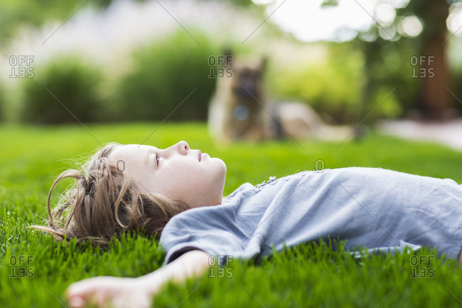 5 year old boy lying down on lush green lawn looking up