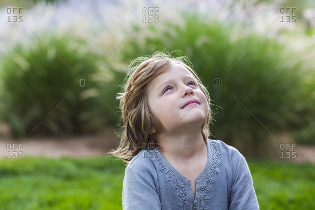 5 year old boy relaxing on lush green lawn looking up