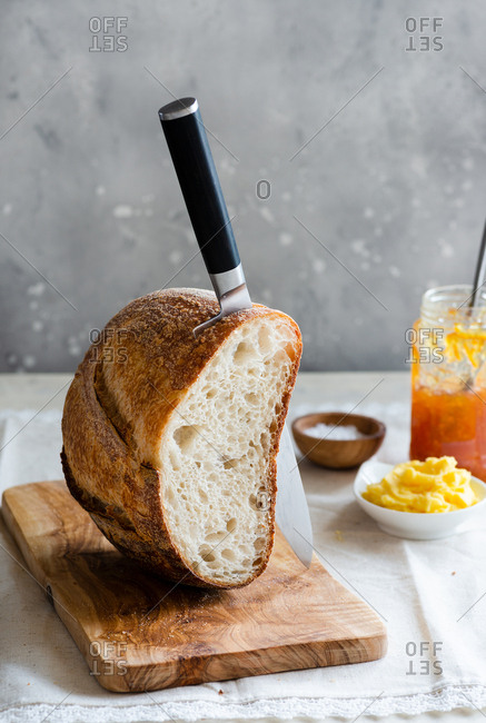 Fresh bread with knife on wooden board