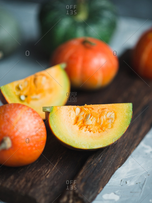 Cut pumpkin on wooden cutting board over gray concrete background