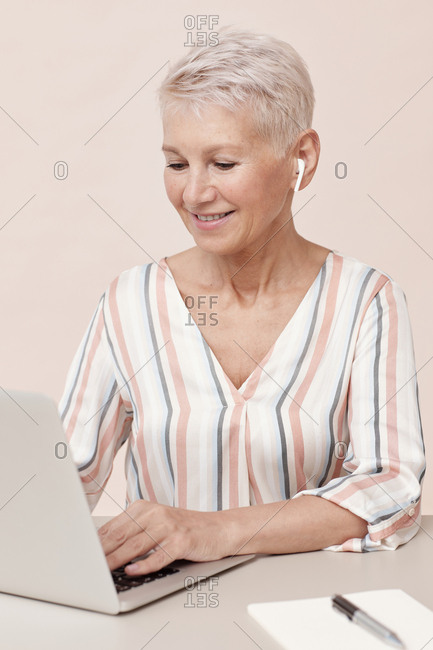 Stylish woman wearing modern wireless earphones working on her computer vertical shot