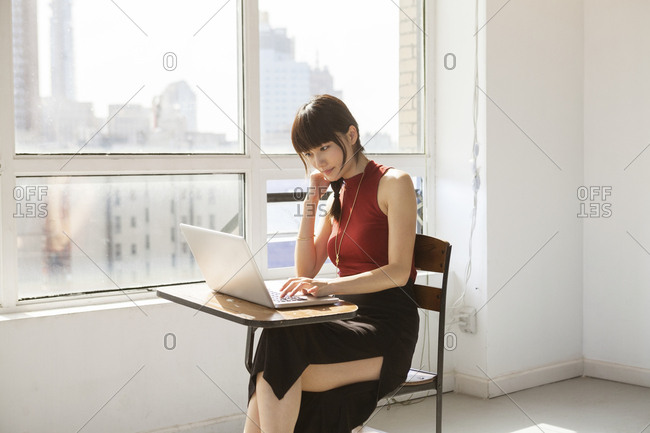Side view of businesswoman working on laptop computer in creative office