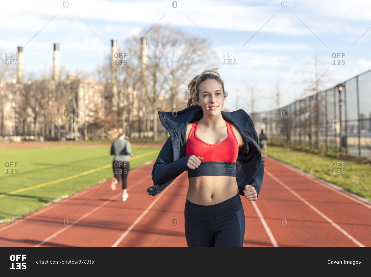 Female athlete running on sports track against sky