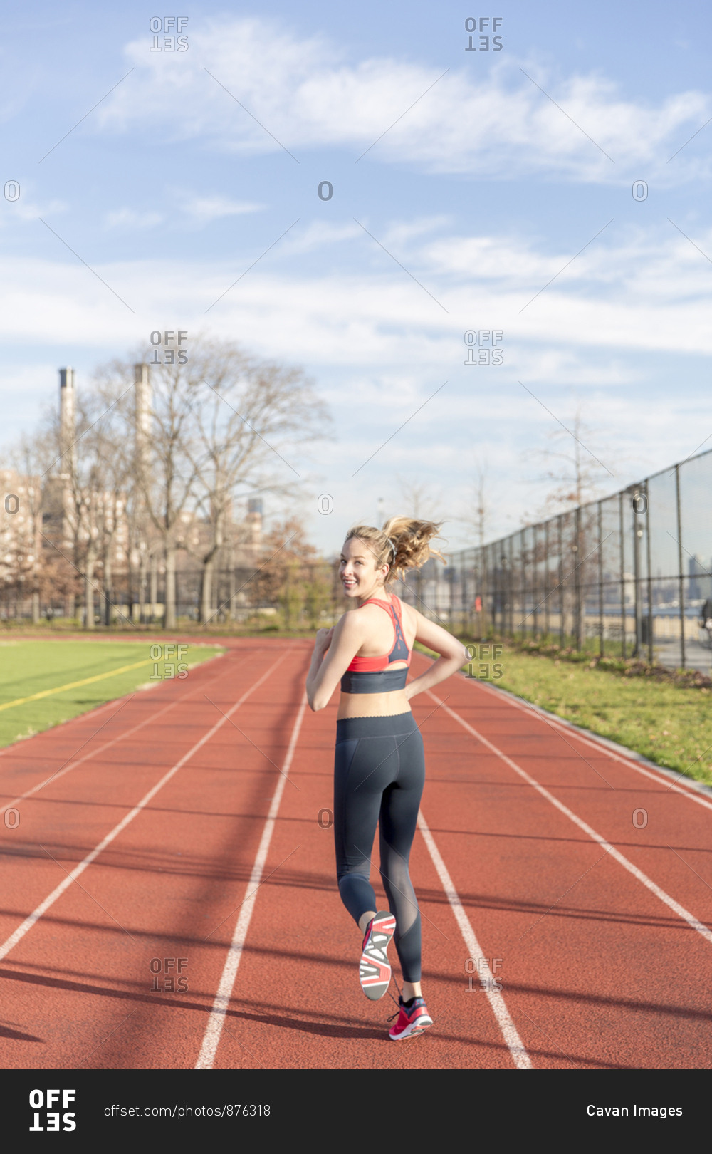 Portrait of athlete running on sports track against sky