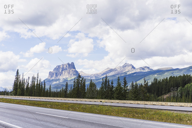 Scenic view of road by mountains against cloudy sky