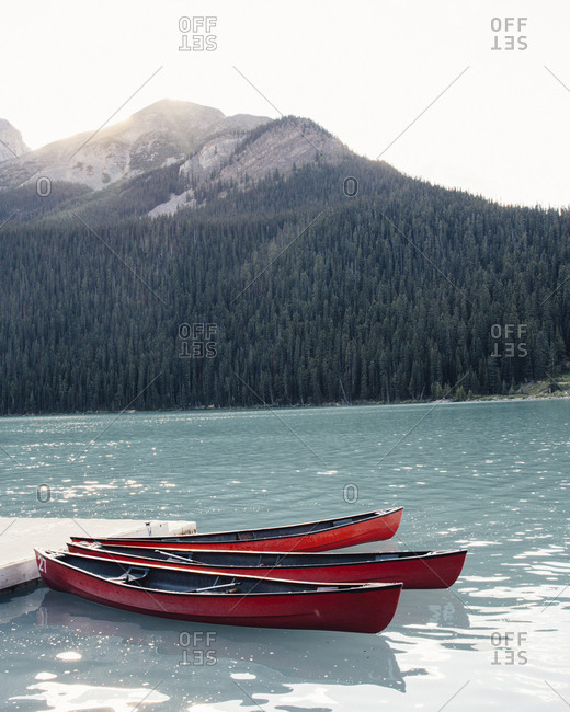 Canoe moored in lake by mountain against clear sky