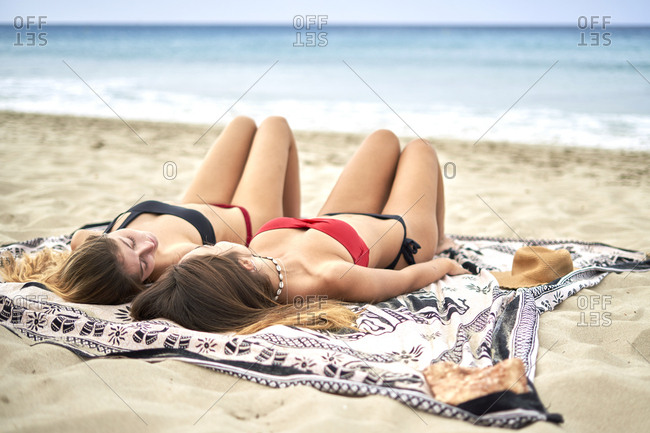 Two young women lying on a towel a beach