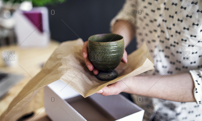 Close-up of woman wrapping an earthenware mug