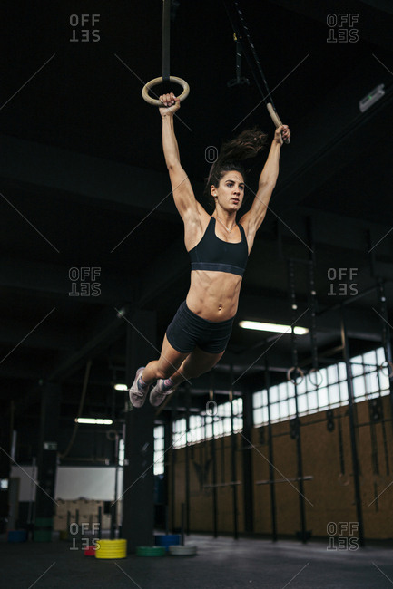 Female athlete hanging on gymnastic rings in gym stock photo