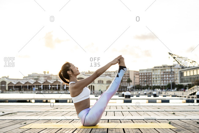 Woman doing boat yoga pose on the beach