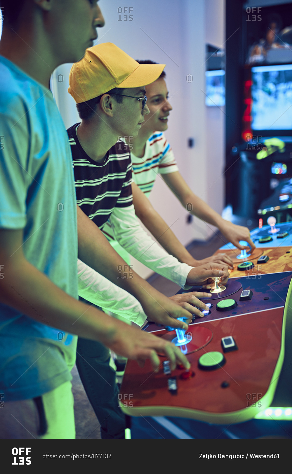 Teenage friends playing with a gaming machine in an amusement arcade