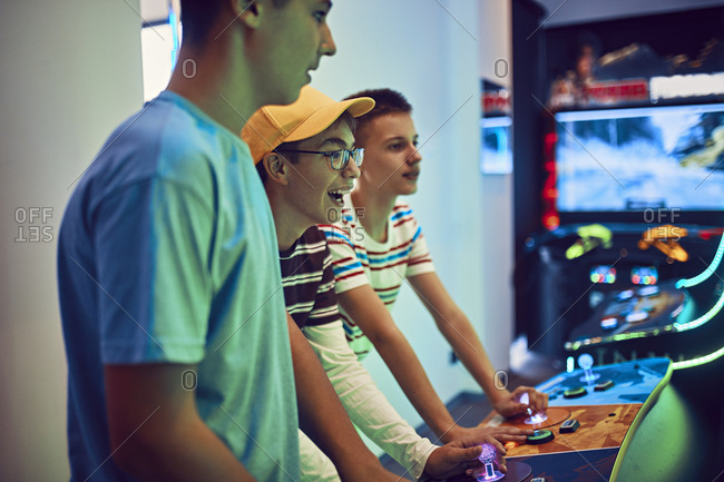 Teenage friends playing with a gaming machine in an amusement arcade