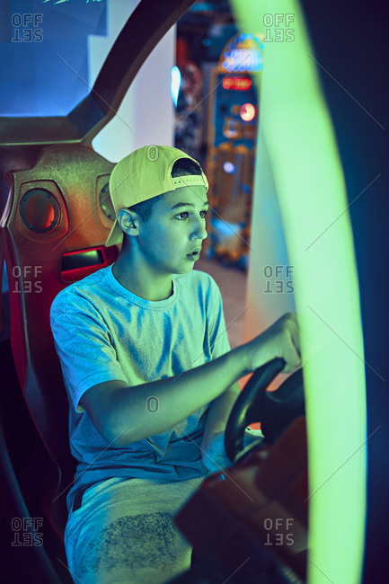 Teenage boy playing with a driving simulator in an amusement arcade