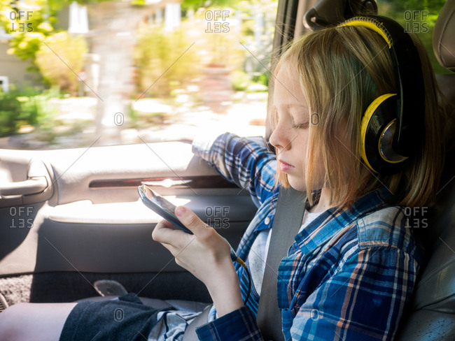 Boy looking at mobile phone while listening music in car