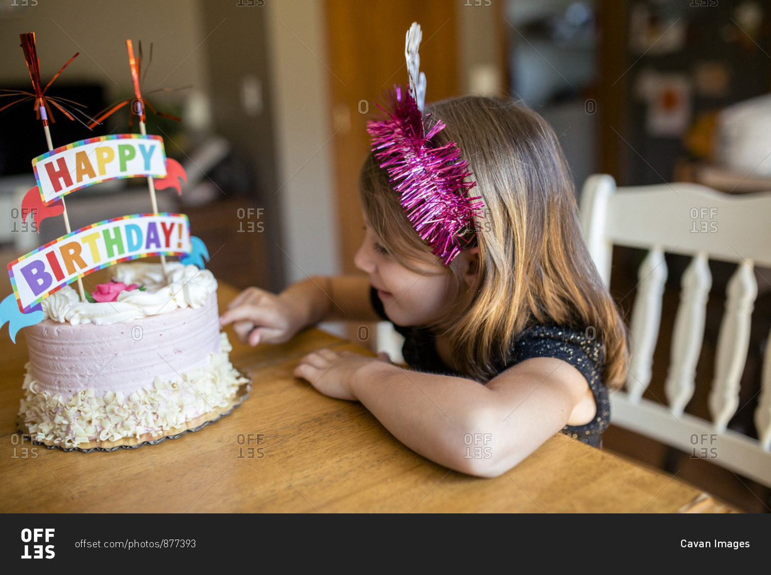 High angle view of girl touching birthday cake while sitting on chair at home