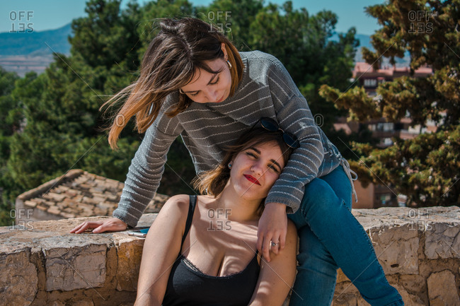 Women embrace and laugh while sitting on the stone