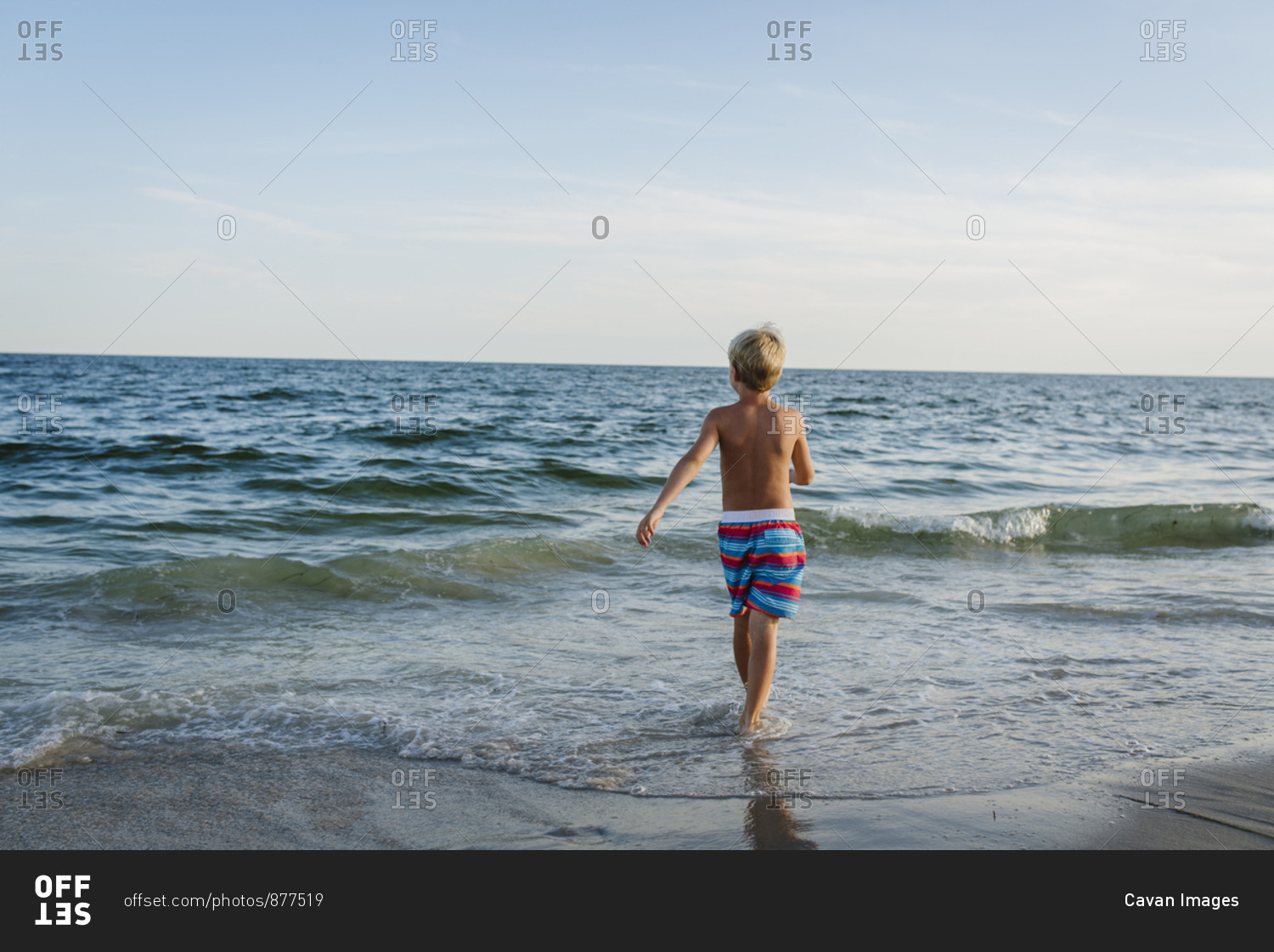 Rear View Of Shirtless Boy Walking At Tobay Beach Towards Sea Against 